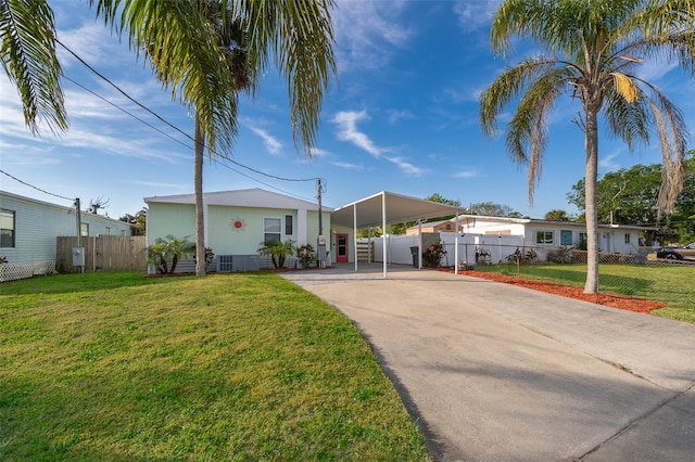 view of front of house featuring concrete driveway, an attached carport, fence, and a front yard