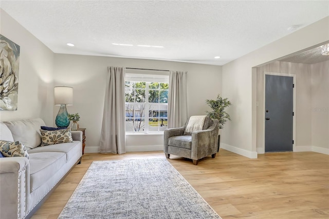 living area featuring baseboards, a textured ceiling, recessed lighting, and light wood finished floors