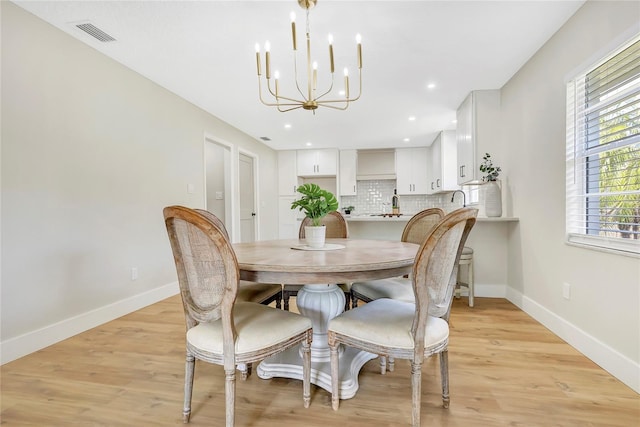 dining room featuring visible vents, a notable chandelier, baseboards, and light wood-type flooring