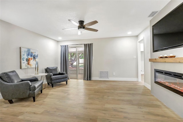 living area featuring light wood-style flooring, ceiling fan, and visible vents