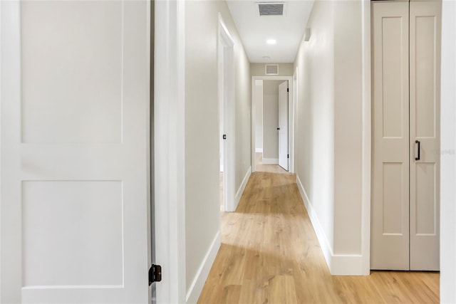corridor with baseboards, visible vents, and light wood-style floors