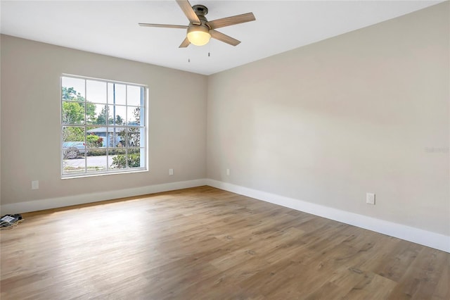 spare room featuring baseboards, wood finished floors, and a ceiling fan