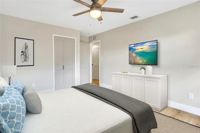bedroom featuring light wood-style floors, baseboards, ceiling fan, and visible vents