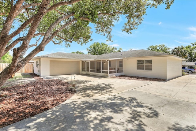 back of property with a sunroom, fence, a garage, and concrete driveway
