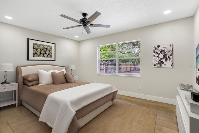 bedroom featuring a ceiling fan, a textured ceiling, light wood-type flooring, baseboards, and recessed lighting