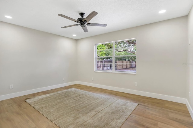 spare room with baseboards, wood finished floors, recessed lighting, and a ceiling fan