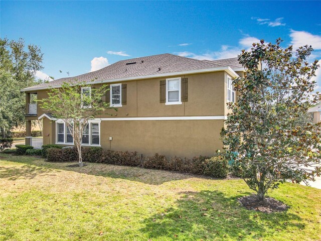 10852 Spider Lily Dr Unit S, Orlando, FL 32832 - back of house featuring stucco siding, a yard, and roof with shingles
