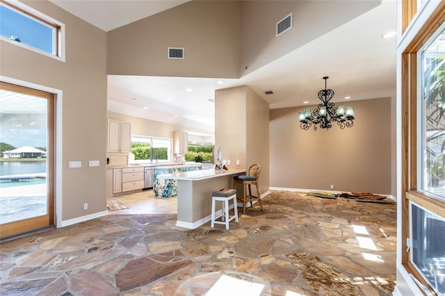 kitchen featuring recessed lighting, stainless steel dishwasher, visible vents, stone floors, and a high ceiling