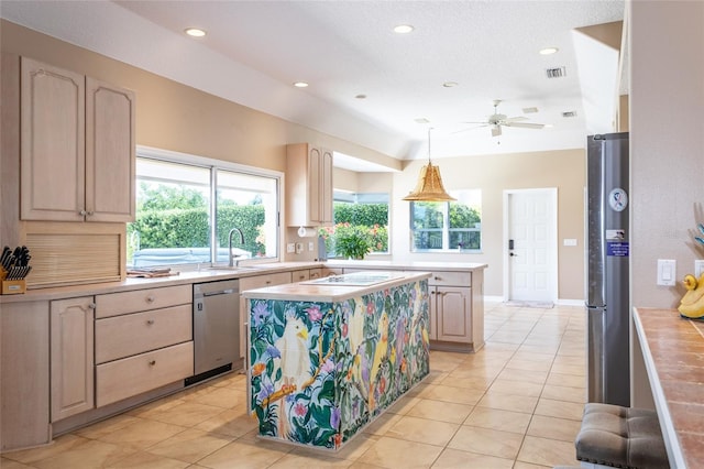 kitchen with stainless steel appliances, light countertops, a kitchen island, a sink, and a ceiling fan