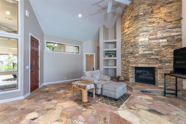 living area with a fireplace, baseboards, stone floors, a ceiling fan, and built in features