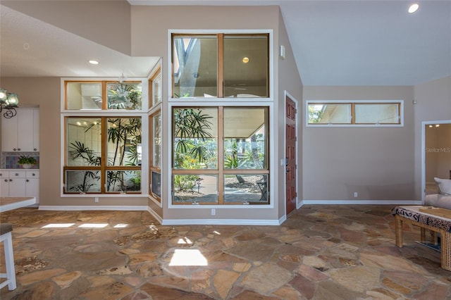 foyer with stone floors, recessed lighting, vaulted ceiling, and baseboards