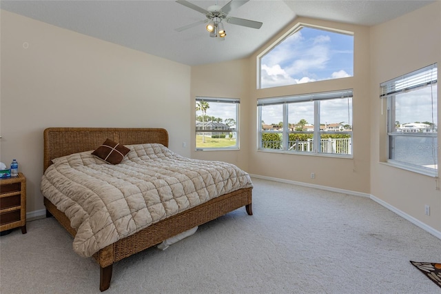 carpeted bedroom with a ceiling fan, multiple windows, high vaulted ceiling, and baseboards