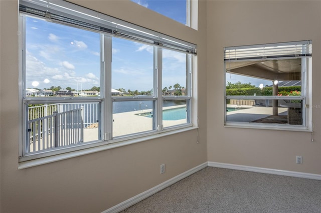 carpeted spare room with plenty of natural light, a water view, and baseboards
