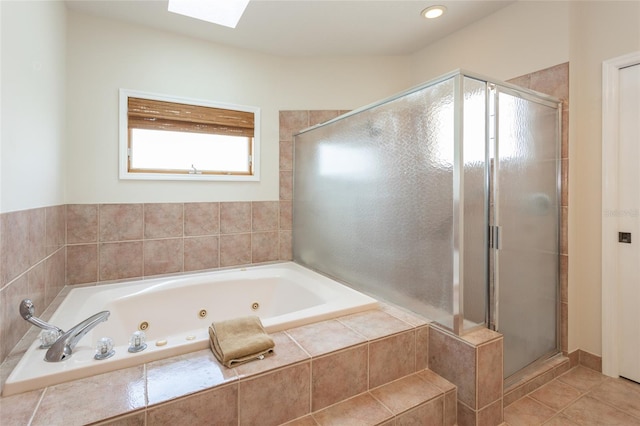 full bath featuring a jetted tub, tile patterned flooring, a stall shower, and a skylight