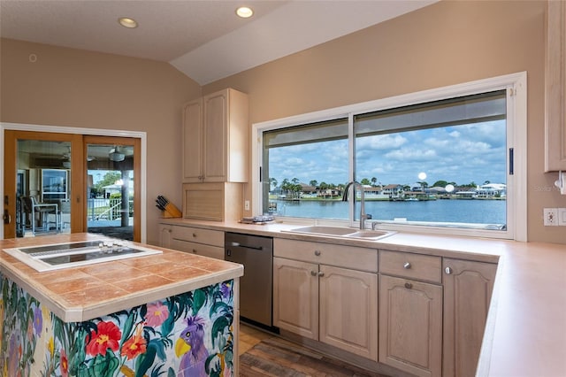 kitchen with stainless steel dishwasher, vaulted ceiling, white electric cooktop, a sink, and tile countertops