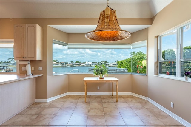 dining space featuring baseboards, a healthy amount of sunlight, and a water view