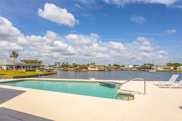 outdoor pool with a residential view, a water view, and a patio area