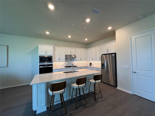 8243 Fenton St, Orlando, FL 32836 - kitchen with appliances with stainless steel finishes, under cabinet range hood, dark wood finished floors, tasteful backsplash, and recessed lighting