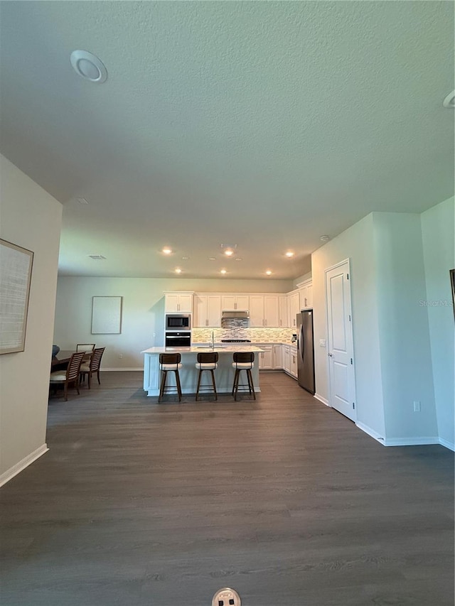 8243 Fenton St, Orlando, FL 32836 - kitchen with stainless steel appliances, a kitchen bar, white cabinets, dark wood-style flooring, and an island with sink