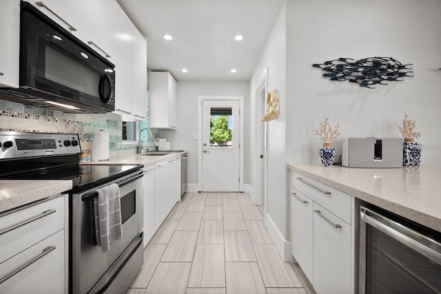 kitchen featuring white cabinets, wine cooler, appliances with stainless steel finishes, a sink, and backsplash