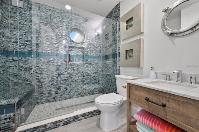 full bathroom with toilet, a stall shower, and vanity