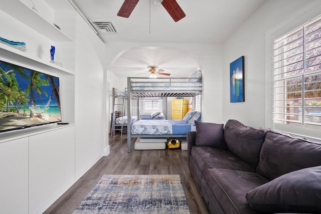 bedroom featuring a ceiling fan, wood finished floors, arched walkways, and visible vents
