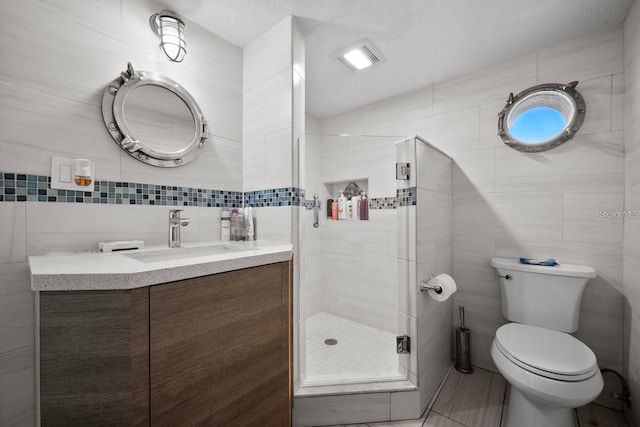 full bathroom with toilet, vanity, tile walls, and a shower stall