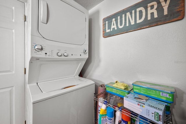 clothes washing area featuring stacked washer and dryer, laundry area, and a textured ceiling