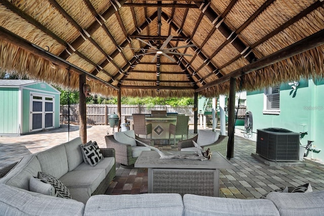 view of patio featuring an outdoor hangout area, an outbuilding, fence, central AC, and a storage shed