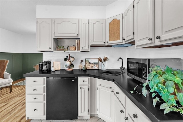 1558 Regal Oak Dr, Kissimmee, FL 34744 - kitchen with decorative backsplash, wainscoting, dark countertops, fridge, and a sink