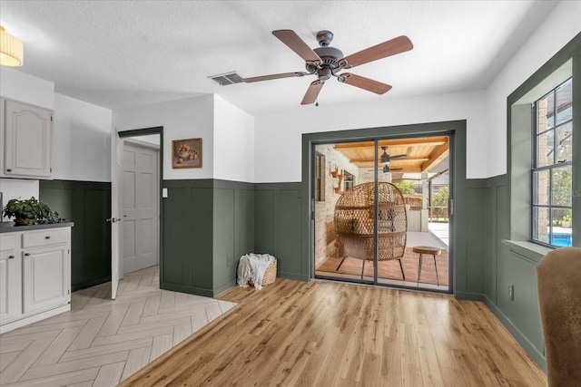 1558 Regal Oak Dr, Kissimmee, FL 34744 - interior space with visible vents, a decorative wall, light wood-style floors, a wainscoted wall, and a ceiling fan
