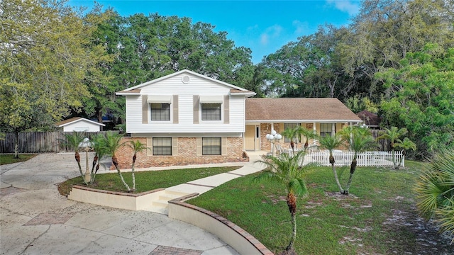 split level home with fence, a front lawn, concrete driveway, covered porch, and brick siding