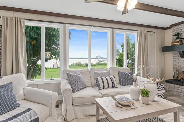living room with beam ceiling, wood finished floors, ceiling fan, and a brick fireplace