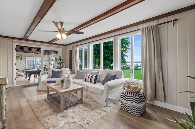 living room with baseboards, beamed ceiling, wood finished floors, and ceiling fan