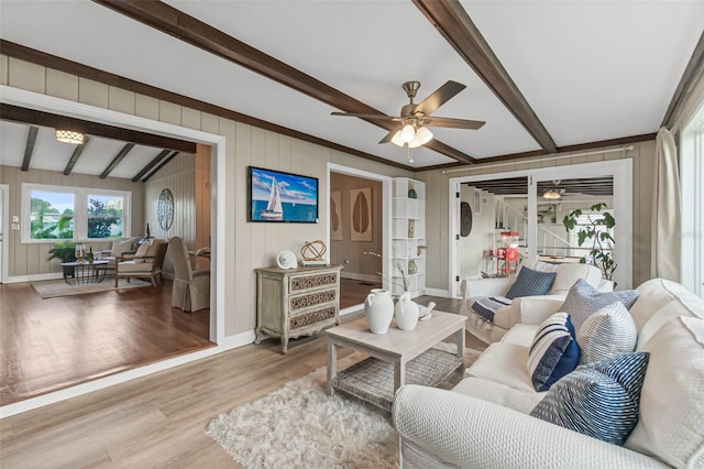 living area with baseboards, light wood-style flooring, a ceiling fan, and beam ceiling