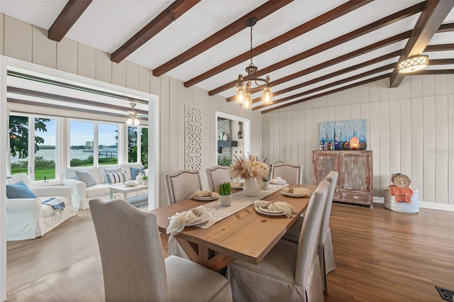 dining area with lofted ceiling with beams, a notable chandelier, and wood finished floors