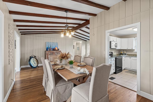 dining area with light wood finished floors, baseboards, a notable chandelier, and lofted ceiling with beams