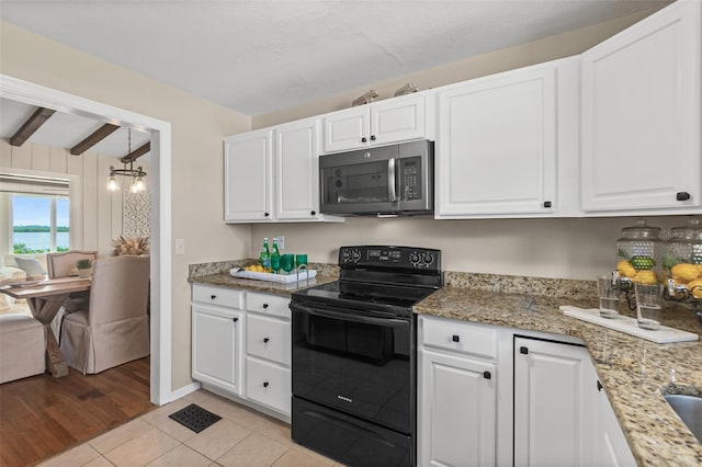 kitchen featuring black electric range oven, stainless steel microwave, light tile patterned floors, light stone counters, and white cabinets