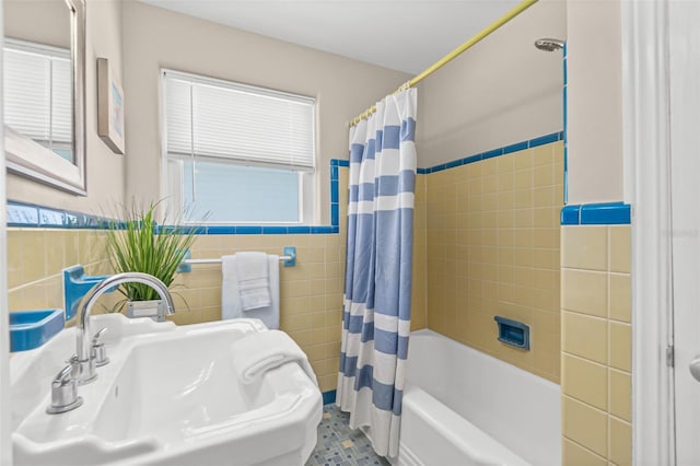 full bathroom with shower / bath combo with shower curtain, a sink, a wainscoted wall, and tile walls