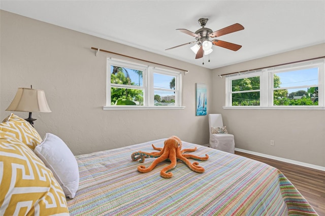 bedroom featuring multiple windows, wood finished floors, ceiling fan, and baseboards