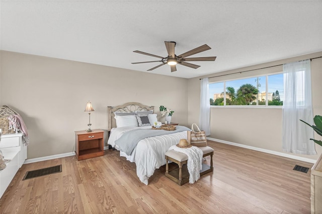 bedroom featuring baseboards, light wood finished floors, and visible vents