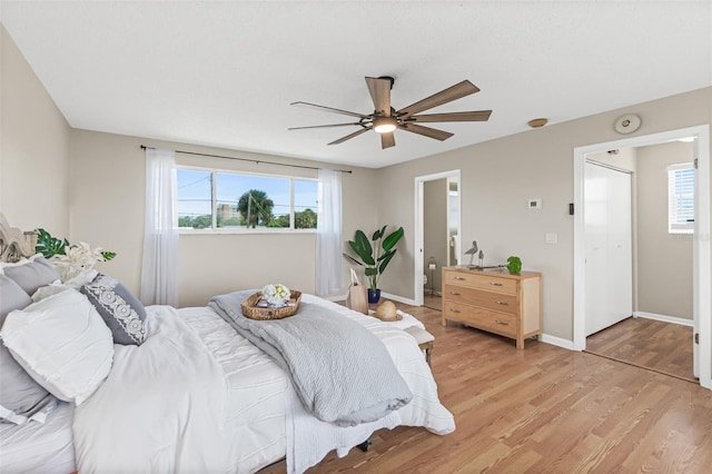 bedroom featuring baseboards, light wood-style floors, and a ceiling fan