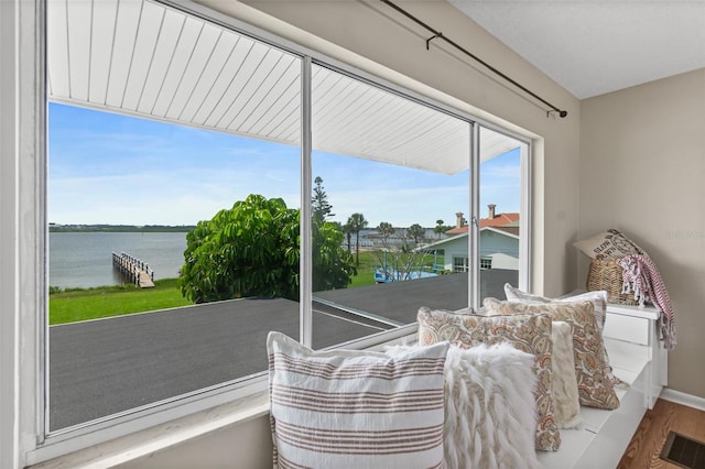 living area featuring baseboards, a water view, visible vents, and wood finished floors