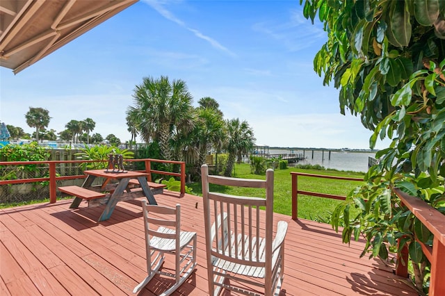 wooden terrace with a water view and a yard