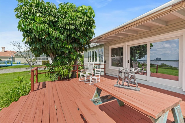 wooden terrace featuring a lawn and a water view