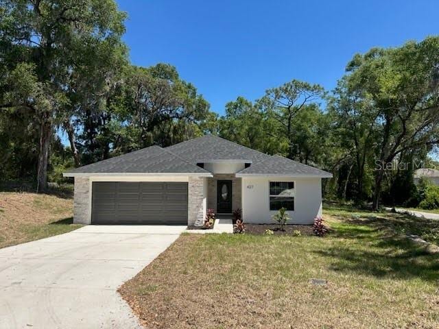 ranch-style house with an attached garage, concrete driveway, stucco siding, and a front lawn