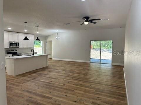 kitchen with open floor plan, appliances with stainless steel finishes, wood finished floors, and baseboards