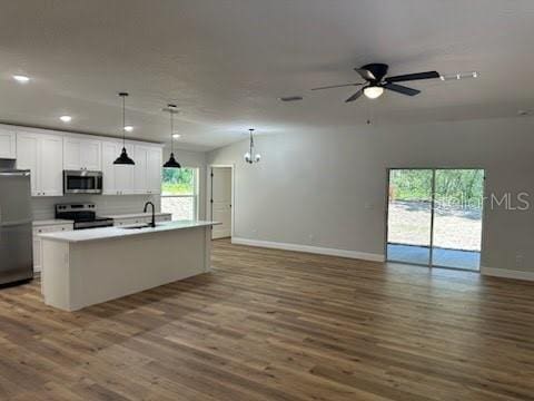kitchen with stainless steel appliances, open floor plan, baseboards, and a sink