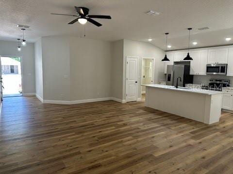 kitchen featuring open floor plan, dark wood-type flooring, white cabinetry, and stainless steel appliances