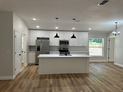 kitchen featuring white cabinetry, light countertops, a sink, stainless steel appliances, and baseboards
